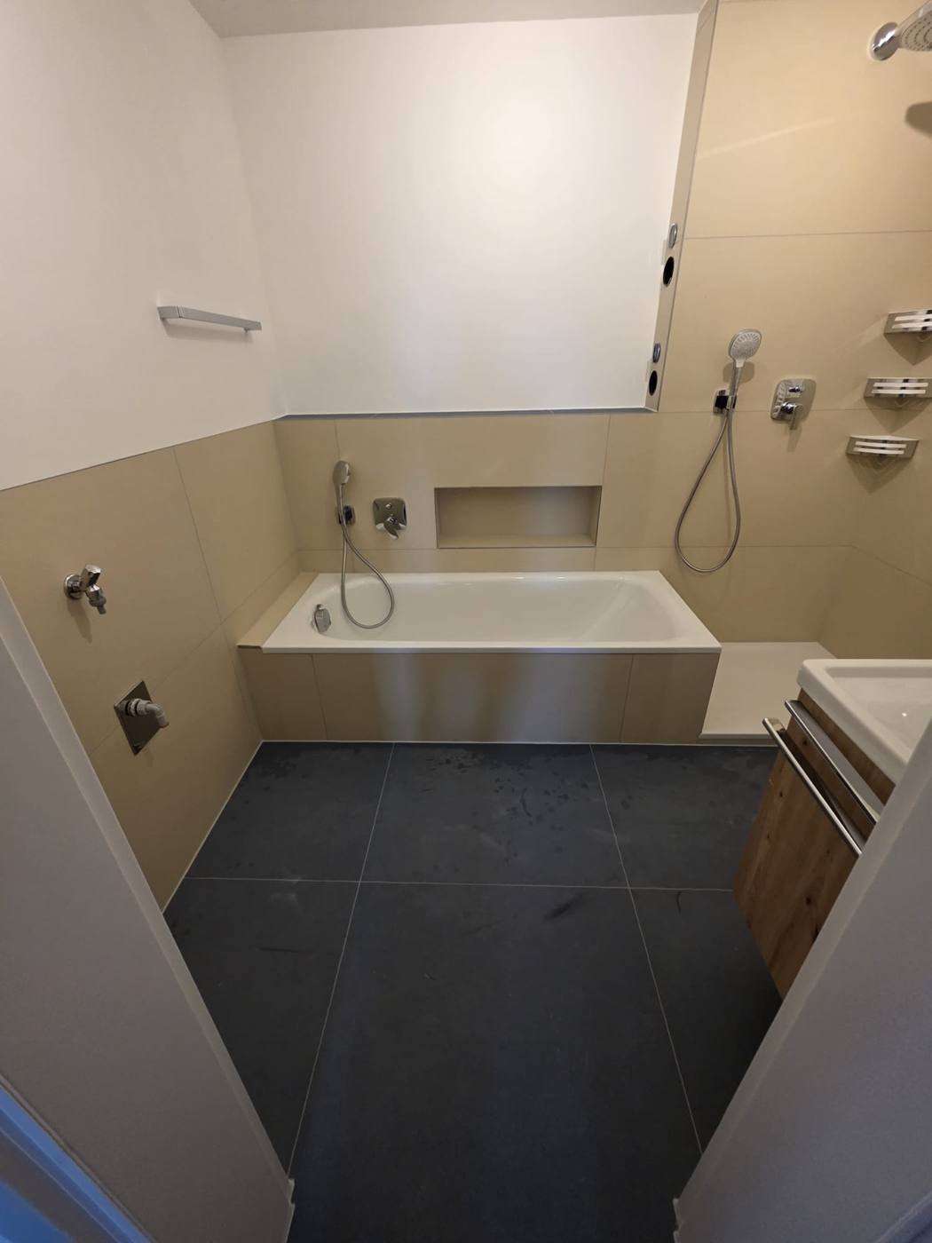 Komplett saniertes Bad mit Badewanne und dunklen Bodenfliesen